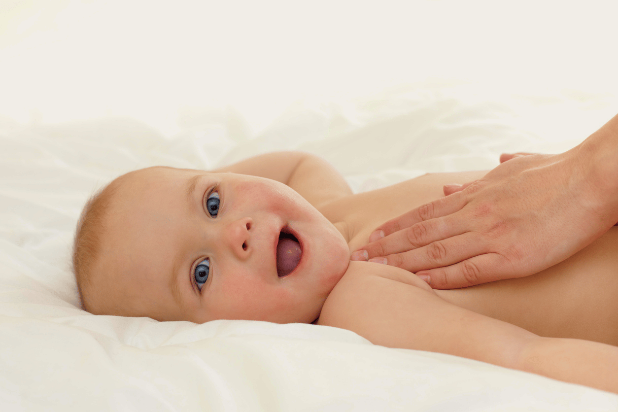 Frauenhände massieren Baby am Oberkörper